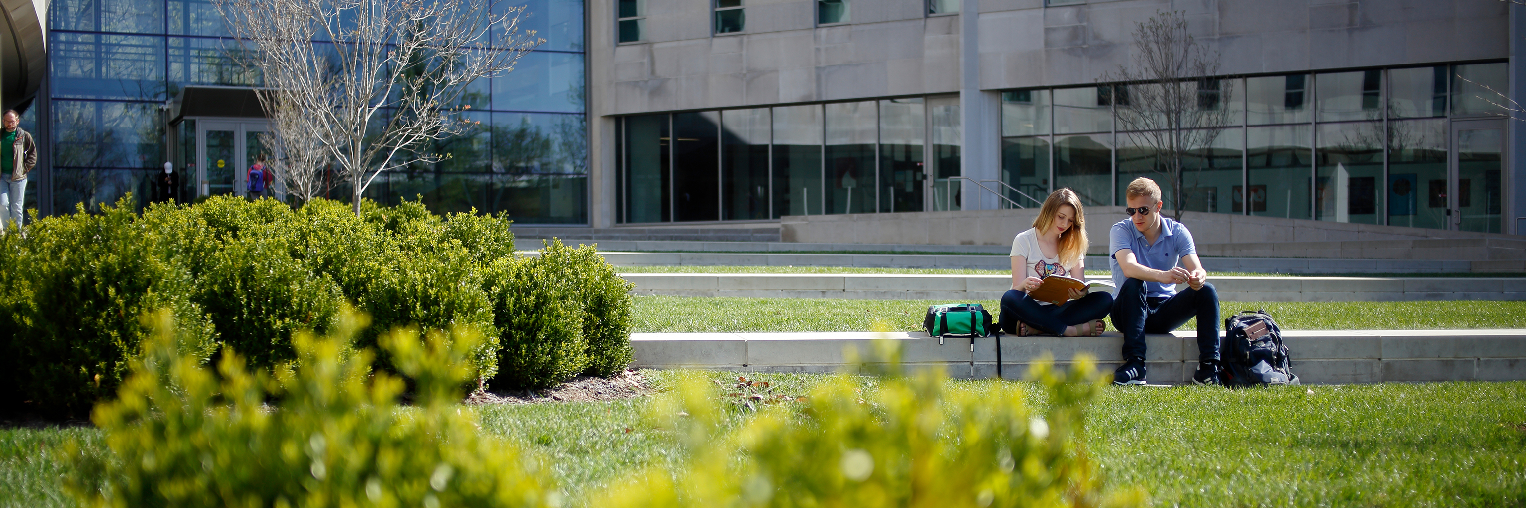 Students sitting outside the Global and International Studies Building on a sunny day.
