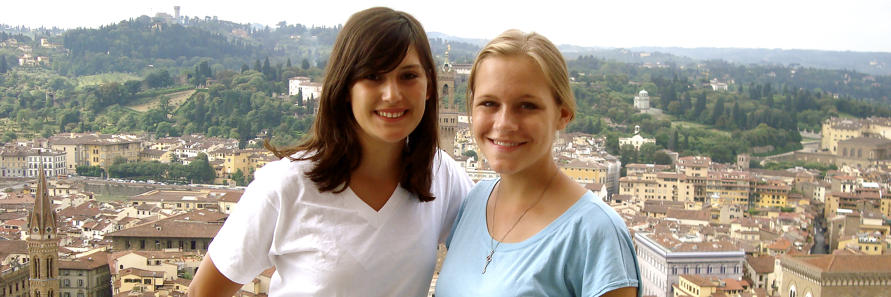 Students pose for photo in front of Italian cityscape.