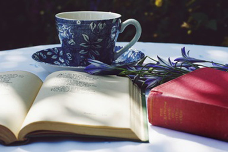 An open book in front of a teacup.