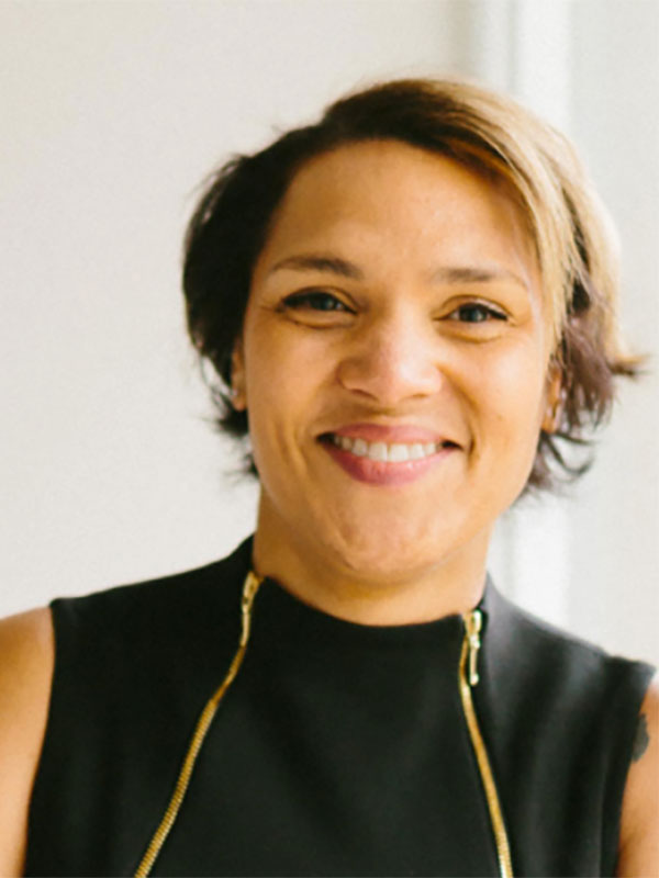 A headshot of Caroline Fache, who wears a black top with a pair of long gold zippers on its front.