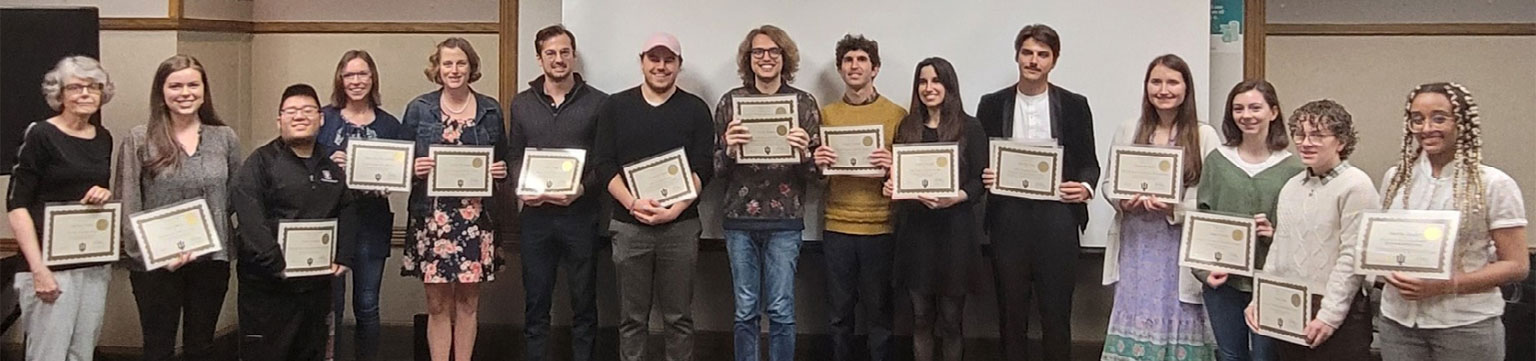 A large group of people hold up their recently earned degree certificates.