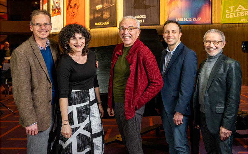 A group of faculty members pose together in the lobby of a theatre.