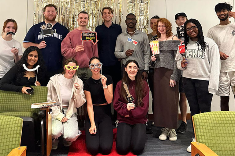 Students pose with fake glasses and Oscar trophies at French movie night.