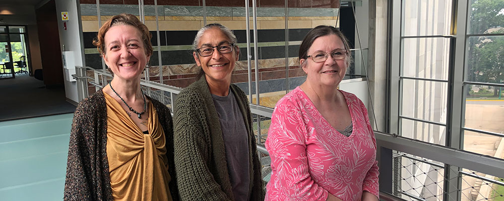 Three new staff members pose together in the GISB building.